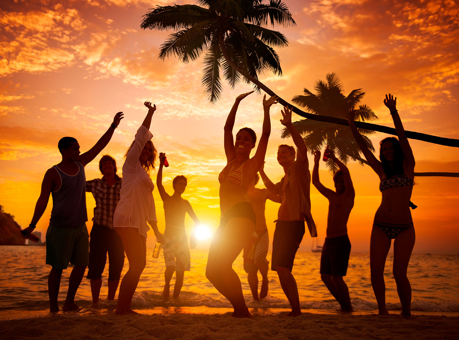 Travelers dancing on the beach at sunset